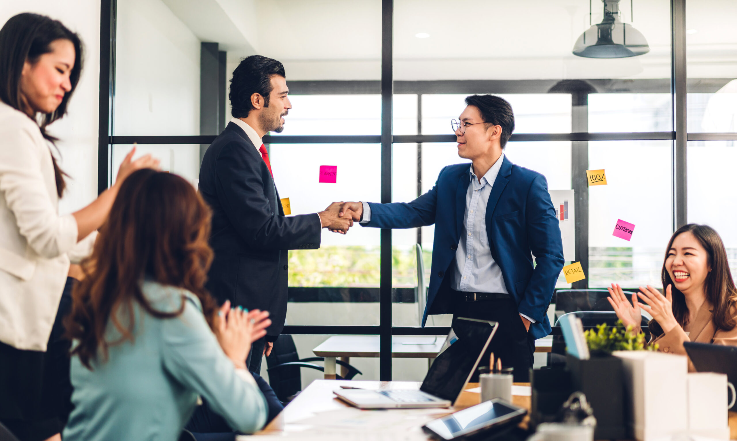 Employee being recognized by boss in meeting room with post its on the wall