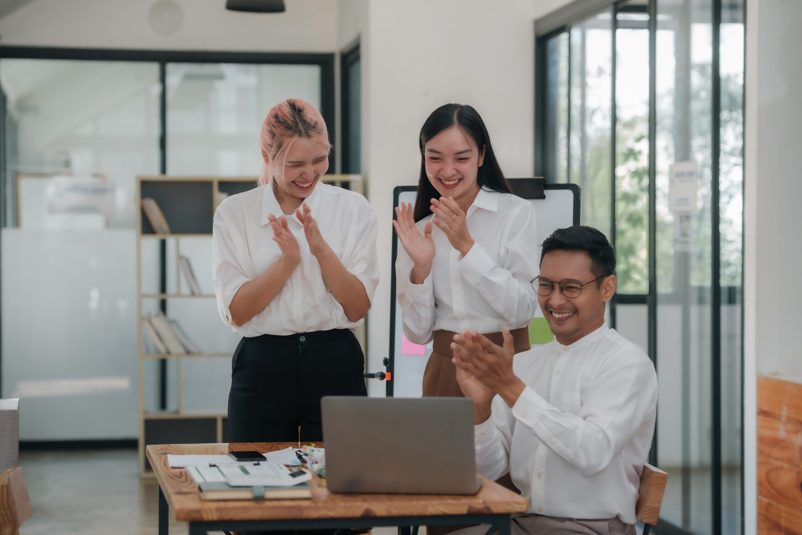Team offering digital employee recognition on laptop in meeting room