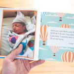Hand holding an opened Kudoboard book for new baby