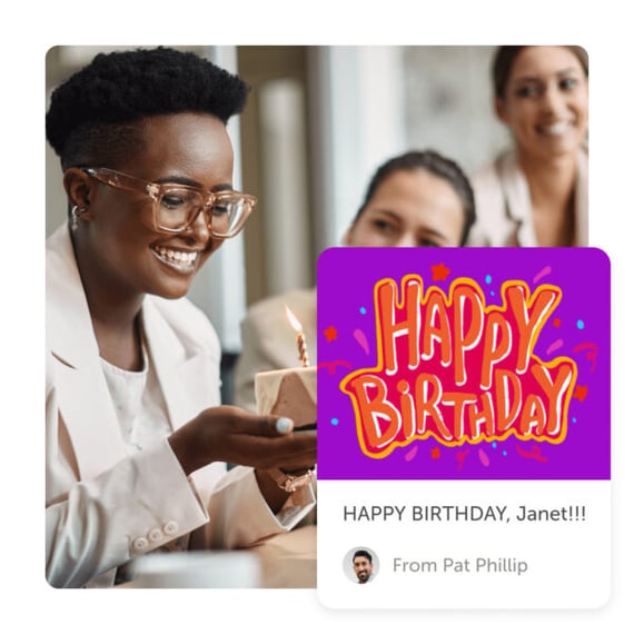 Woman smiling holding cake with 'Happy Birthday' message from a group birthday card by Kudoboard