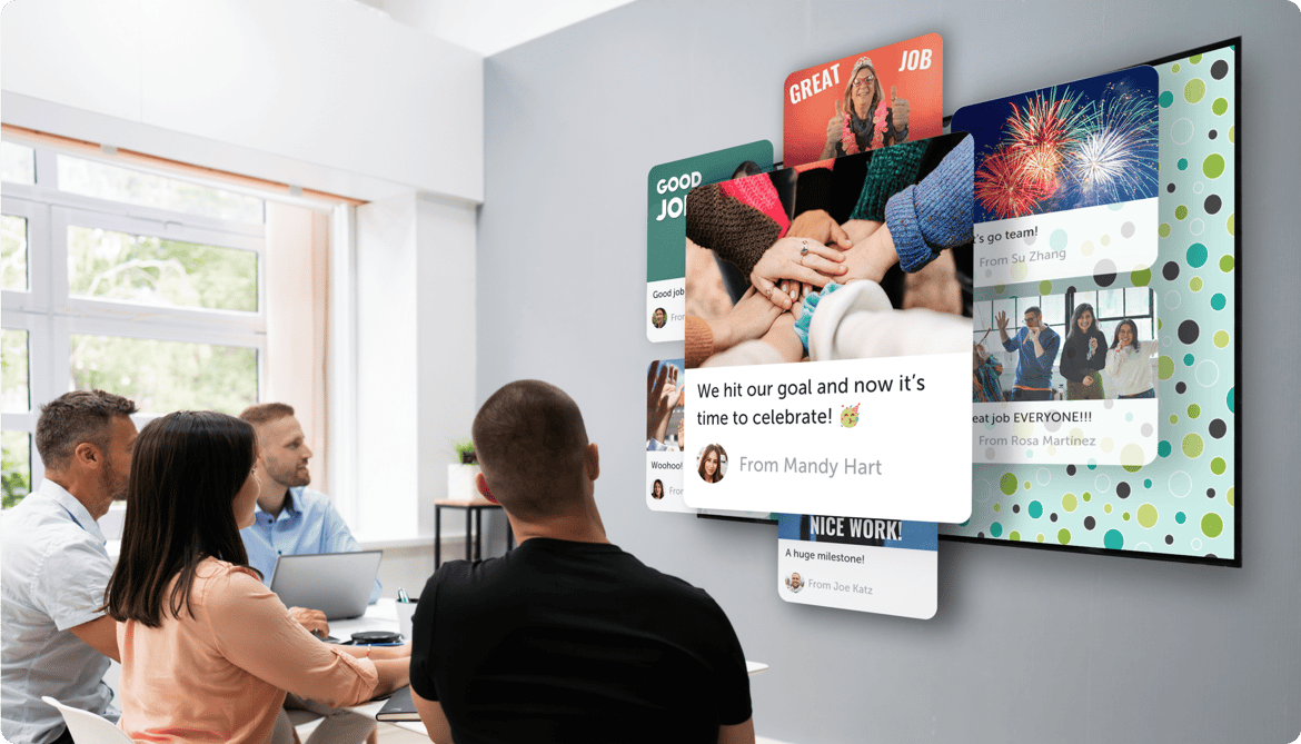 A group inside an office looking at a big screen displaying a kudoboard filled with appreciation for employees