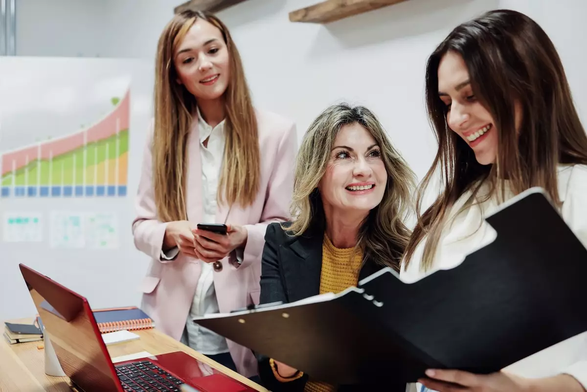 Three women looking at documents in an office.
